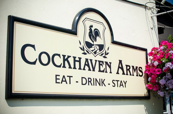 A sign for Cockhaven Arms with the text "EAT - DRINK - STAY".