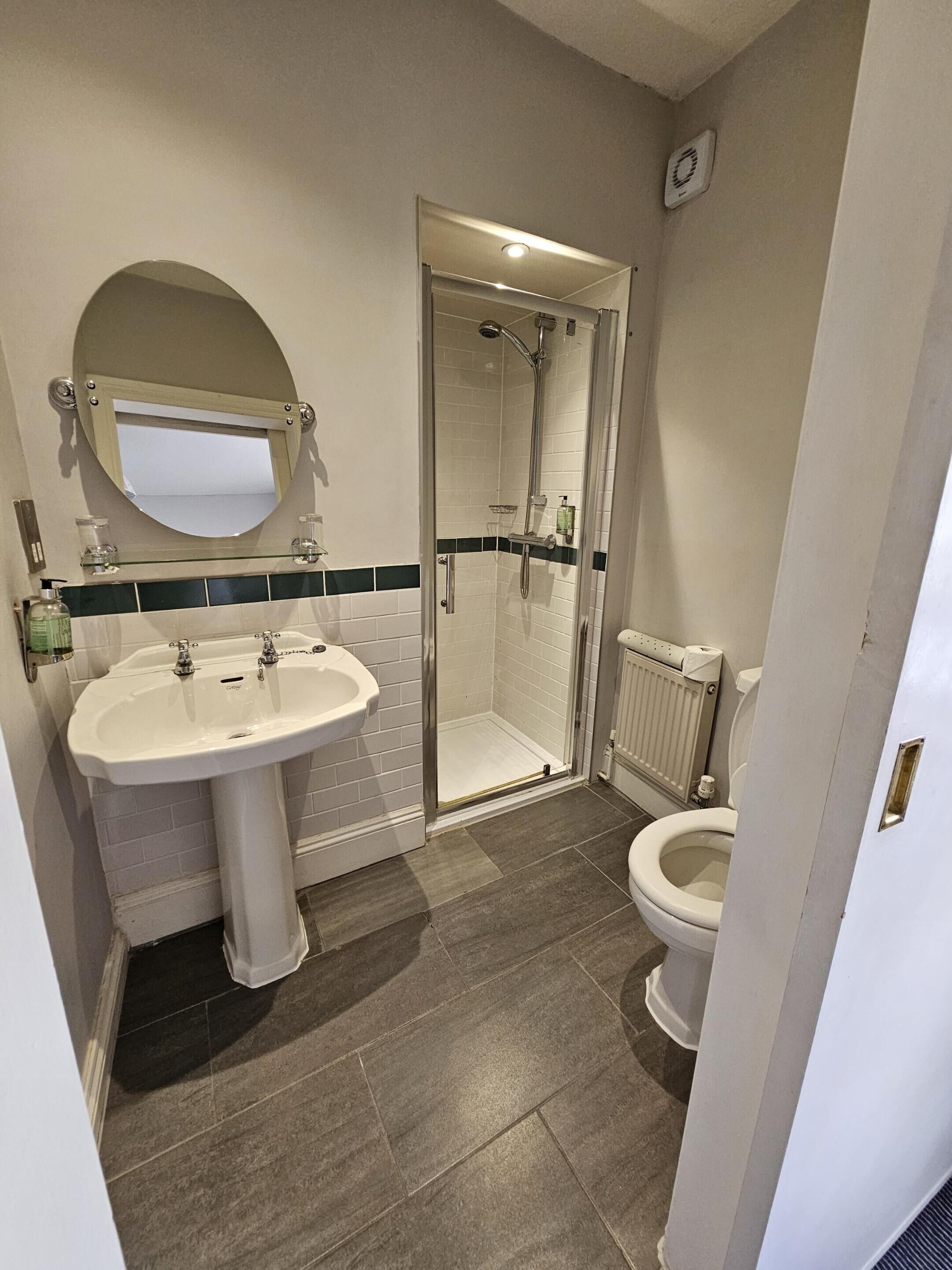A bathroom with a pedestal sink, a glass-enclosed shower, and a toilet.