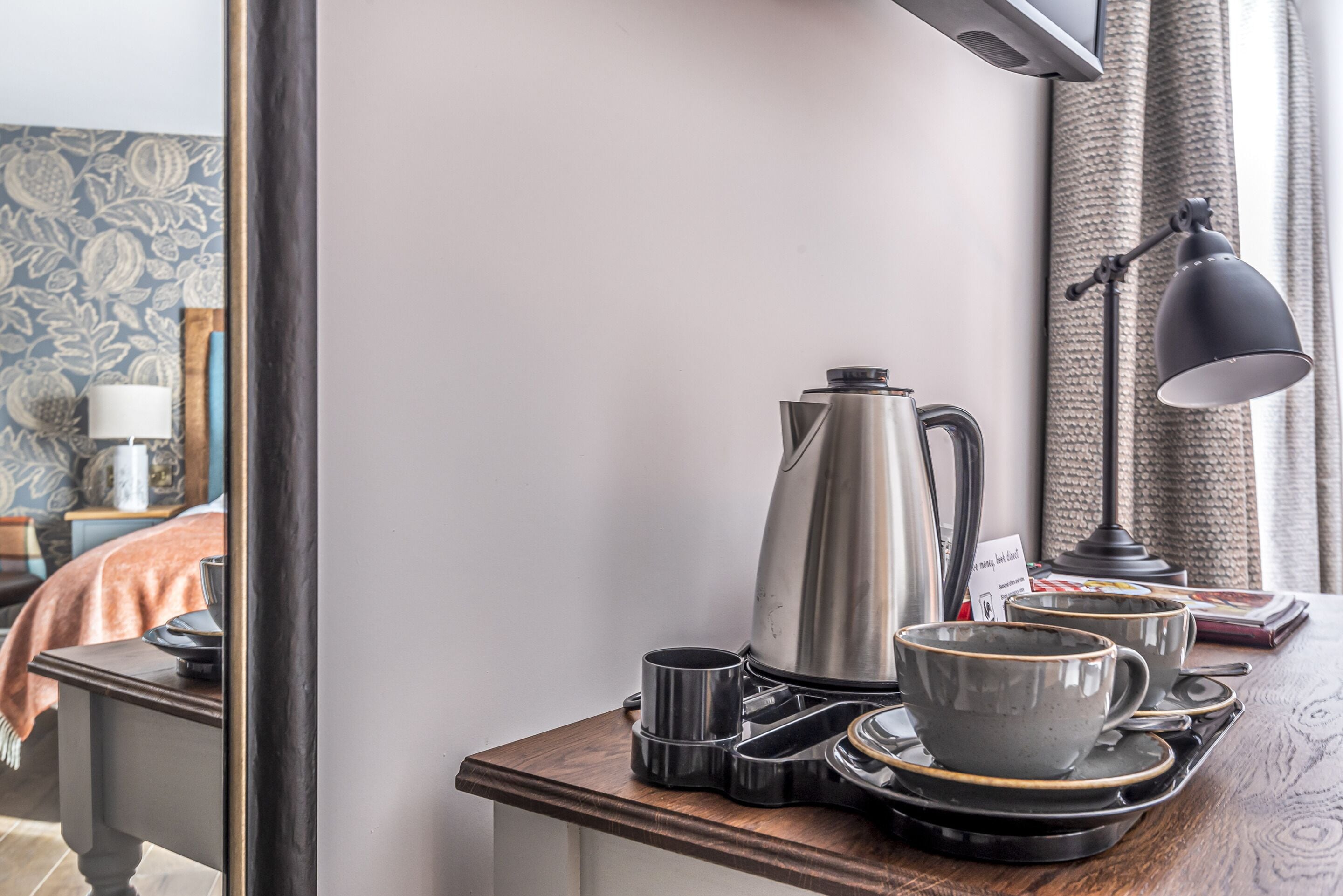 A neatly arranged breakfast setup with a coffee pot, cups, and a tray on a wooden table, reflecting a modern and clean room design.