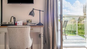 A room with a desk, a chair, a television, a lamp, and a view of the outdoors. - Cockhaven Arms (Teignmouth)