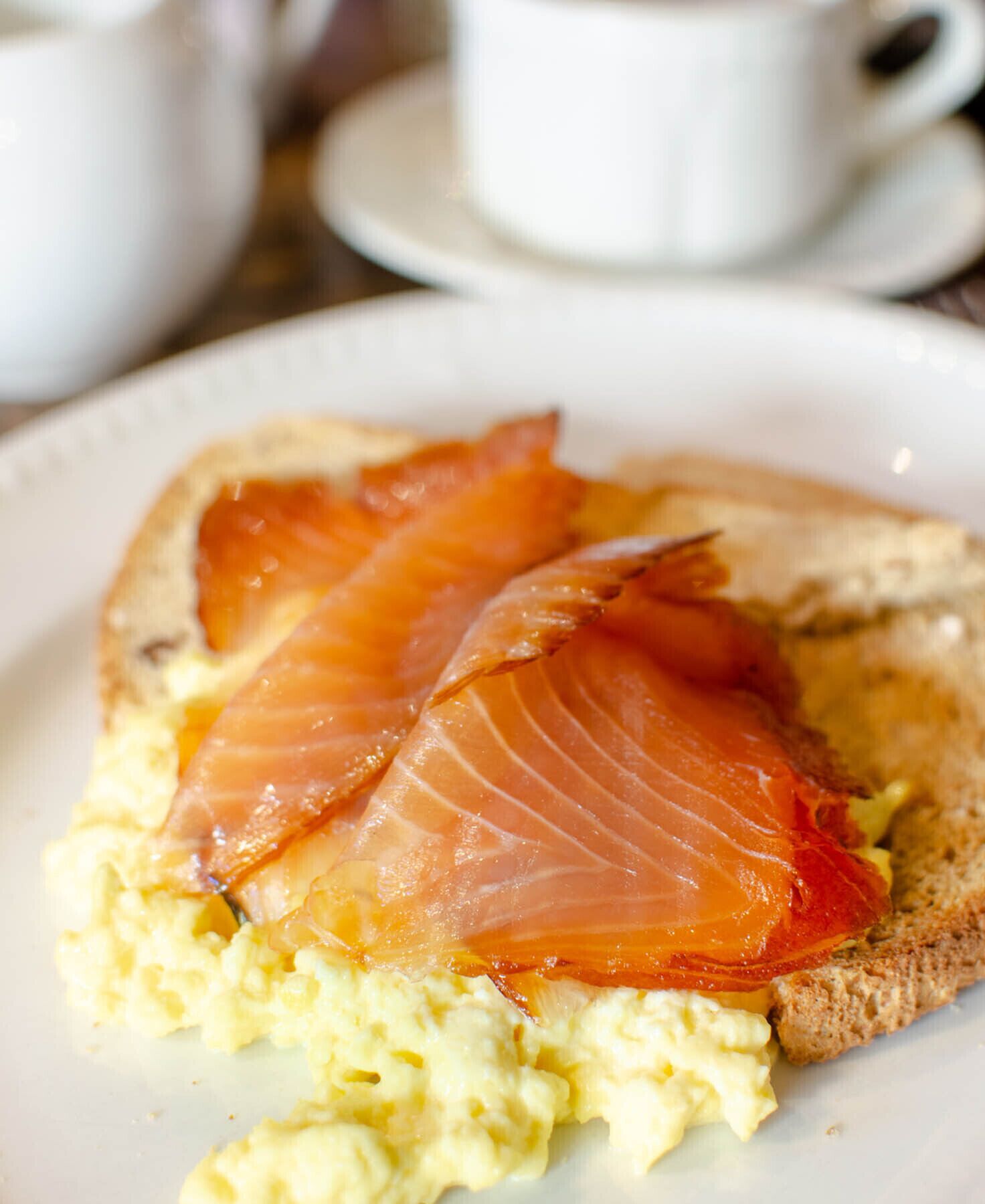 A plate with scrambled eggs and smoked salmon on toast.