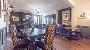 A dining area with wooden tables and patterned chairs, a chandelier, and framed pictures on the walls. - Cockhaven Arms (Teignmouth)