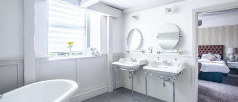 Un baño moderno con una bañera independiente, dos lavamanos y dos espejos montados en la pared.