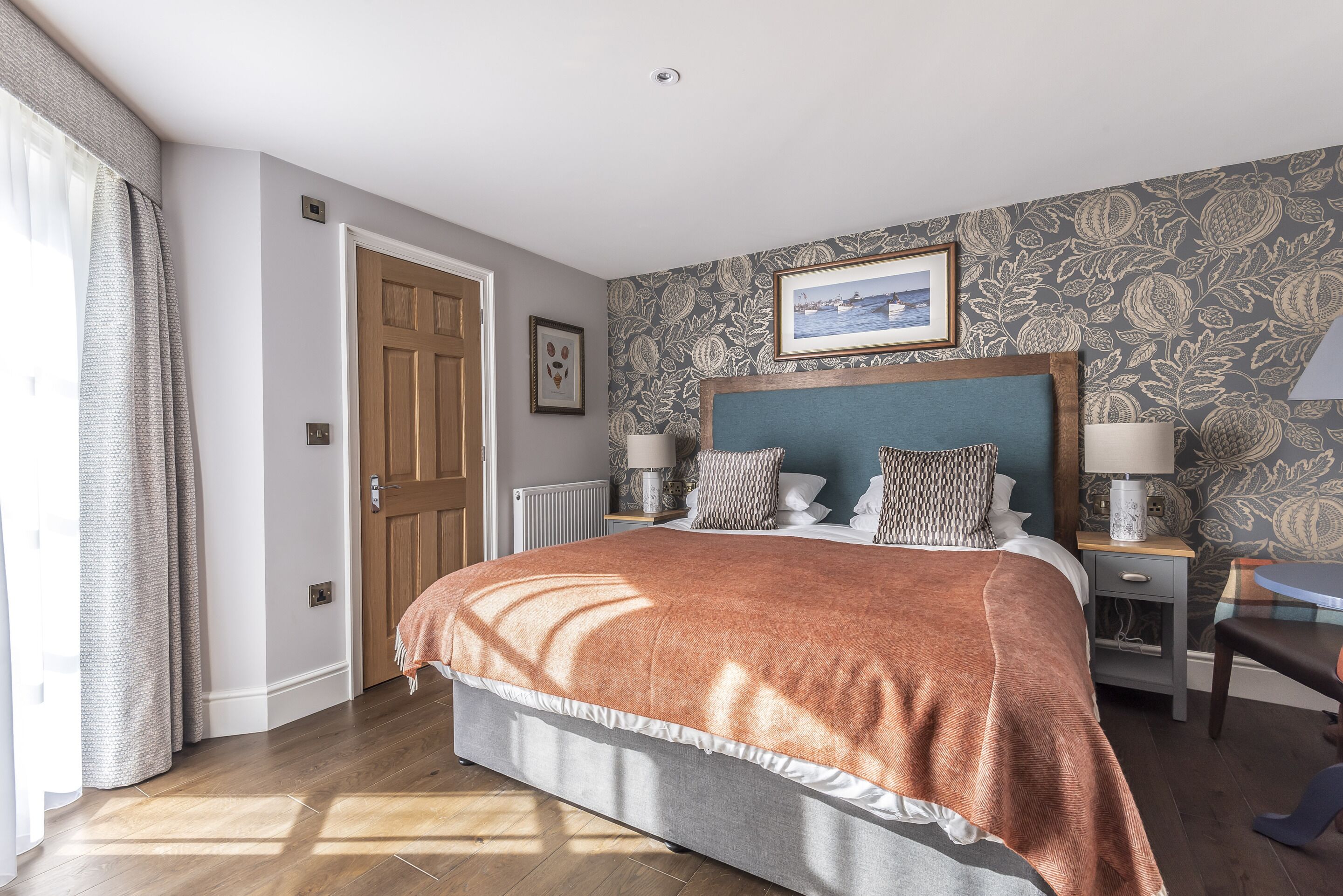 A neatly arranged bedroom with a bed, bedside tables, and a framed picture on the wall.