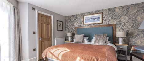 A neatly arranged bedroom with a bed, bedside tables, and a framed picture on the wall.