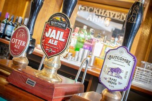Un bar con tres grifos de cerveza etiquetados como 'Otter Ale', 'Jail Ale' y 'Butcombe Rare Breed'.