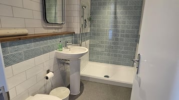 Un baño con inodoro, lavamanos y ducha.