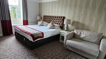 Een hotelkamer met een groot bed, een bank, een nachtkastje en een raam met gordijnen.