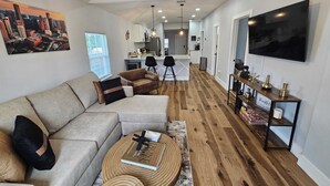 A modern living room with a sectional sofa, a coffee table, and a cityscape painting. - ~ Houston Heights 4-plex with patio ~ (Houston)