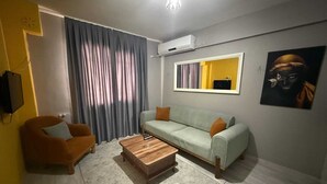 Una sala de estar con un sofá, una mesa de centro, un televisor y un cuadro en la pared.