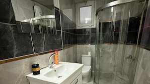 Un baño con tocador blanco, cabina de ducha con mampara de vidrio y un inodoro.
