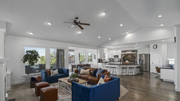 A spacious living room with a blue sofa, a coffee table, and a fireplace. There is a kitchen area with a refrigerator and a dining table. - Luxury - 6000sqft- Sleeps 22+ Basketball, Billiards, Theater, Game, PrincessRoom (Layton)