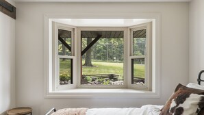 A bedroom with a bay window overlooking a grassy area. - Amazing views, hot tub/outdoor fireplace, countryside, farm (Navarre)