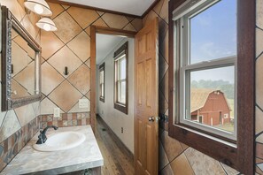 A bathroom with a sink, mirror, and window. - Amazing views, hot tub/outdoor fireplace, countryside, farm with calves & goats. (Navarre)