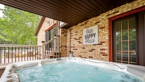 A hot tub with a sign reading "Our Happy Place" on a brick wall, a wooden deck, and a view of trees. - Amazing views, hot tub/outdoor fireplace, countryside, farm (Navarre)