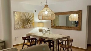 Un espace repas comprenant une table en bois, des chaises et un luminaire suspendu.