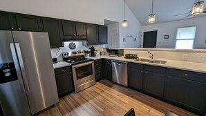 A modern kitchen with stainless steel appliances, dark cabinetry, and a white countertop.