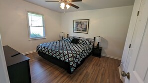 Ein Schlafzimmer mit Bett, Nachttischlampen, Deckenventilator, Fenster und Tür.