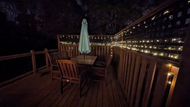 An outdoor deck with wooden furniture and string lights.