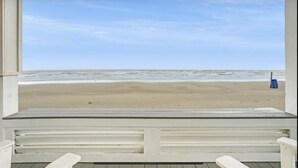 Uitzicht op het strand vanaf een overdekte plek met een bank.