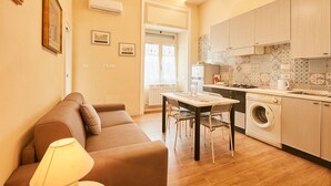 Un espacio habitable compacto con sofá, mesa de comedor y lavadora.