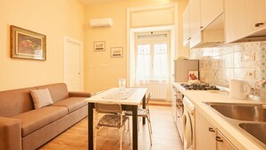 Una cocina compacta con comedor, un sofá y una ventana con cortinas.