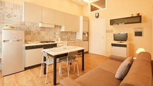 Una cocina compacta con comedor, sofá y televisor.