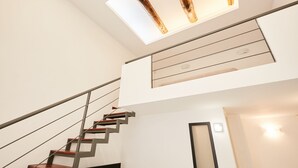 Un escalier moderne avec des finitions en bois et une lucarne au-dessus.
