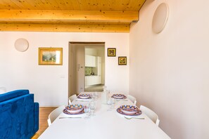 A dining area with a white table set for four, blue chairs, and a wooden ceiling. - Nova Stylish House in center (Naples)