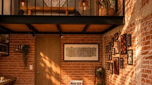 A loft-style room with exposed brick walls, a wooden dining table, and a large window. - TinyChillHouse (Mineral del Monte)