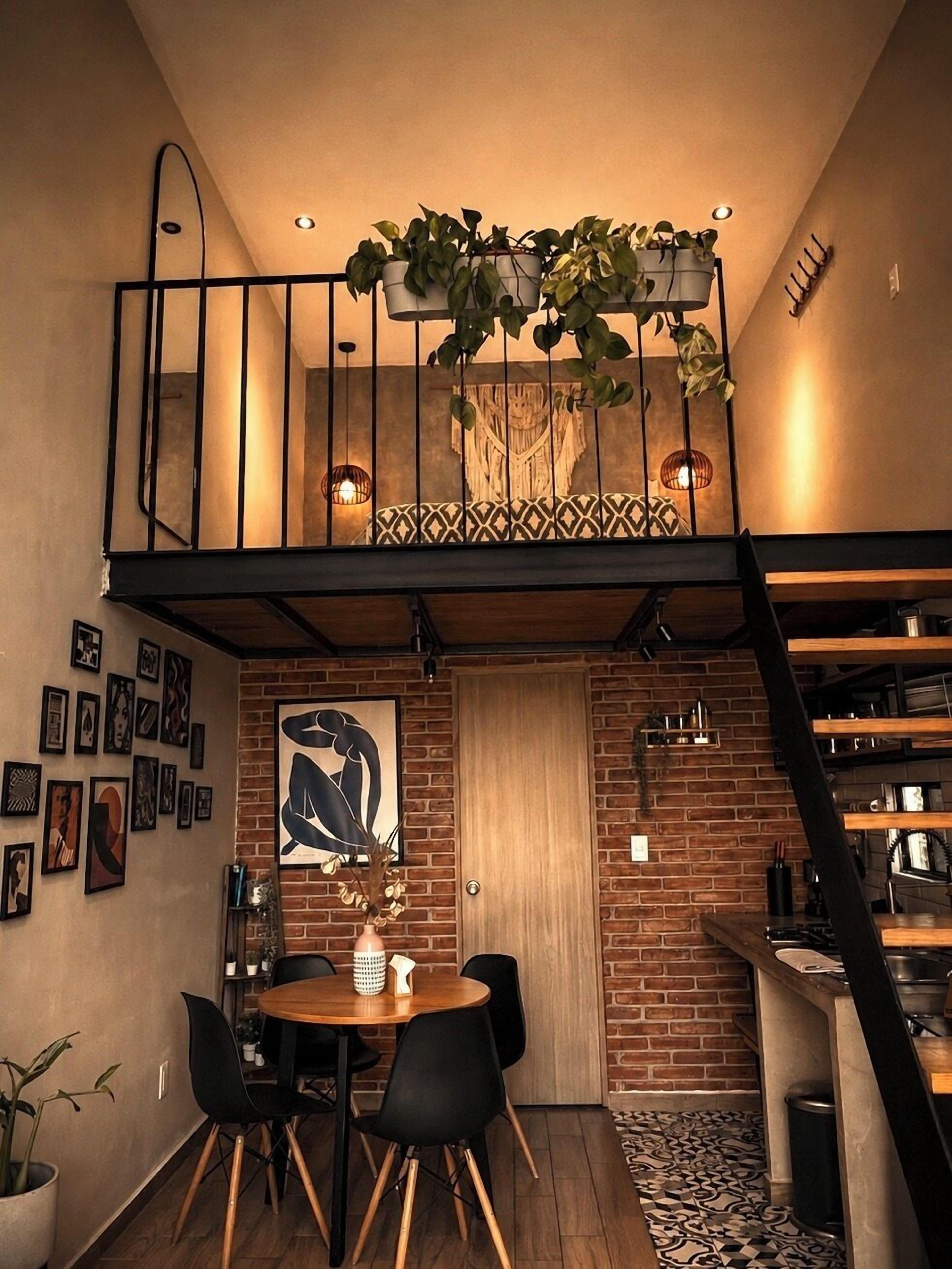 A loft-style dining area with a brick wall, a wooden door, and a staircase.