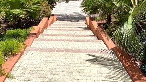 A paved pathway leading to a beach with palm trees and a view of a coastal town. - Luna Sul Mare - 2 Bed 2.5 Bath Condo with gorgeous ocean view! (Sint Maarten)