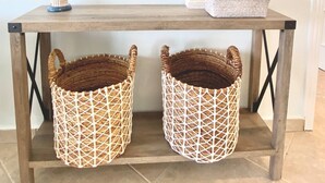 A wooden table with a round mirror above it, two wicker baskets below, and a small decorative item on the table. - Luna Sul Mare - 2 Bed 2.5 Bath Condo with gorgeous ocean view! (Sint Maarten)