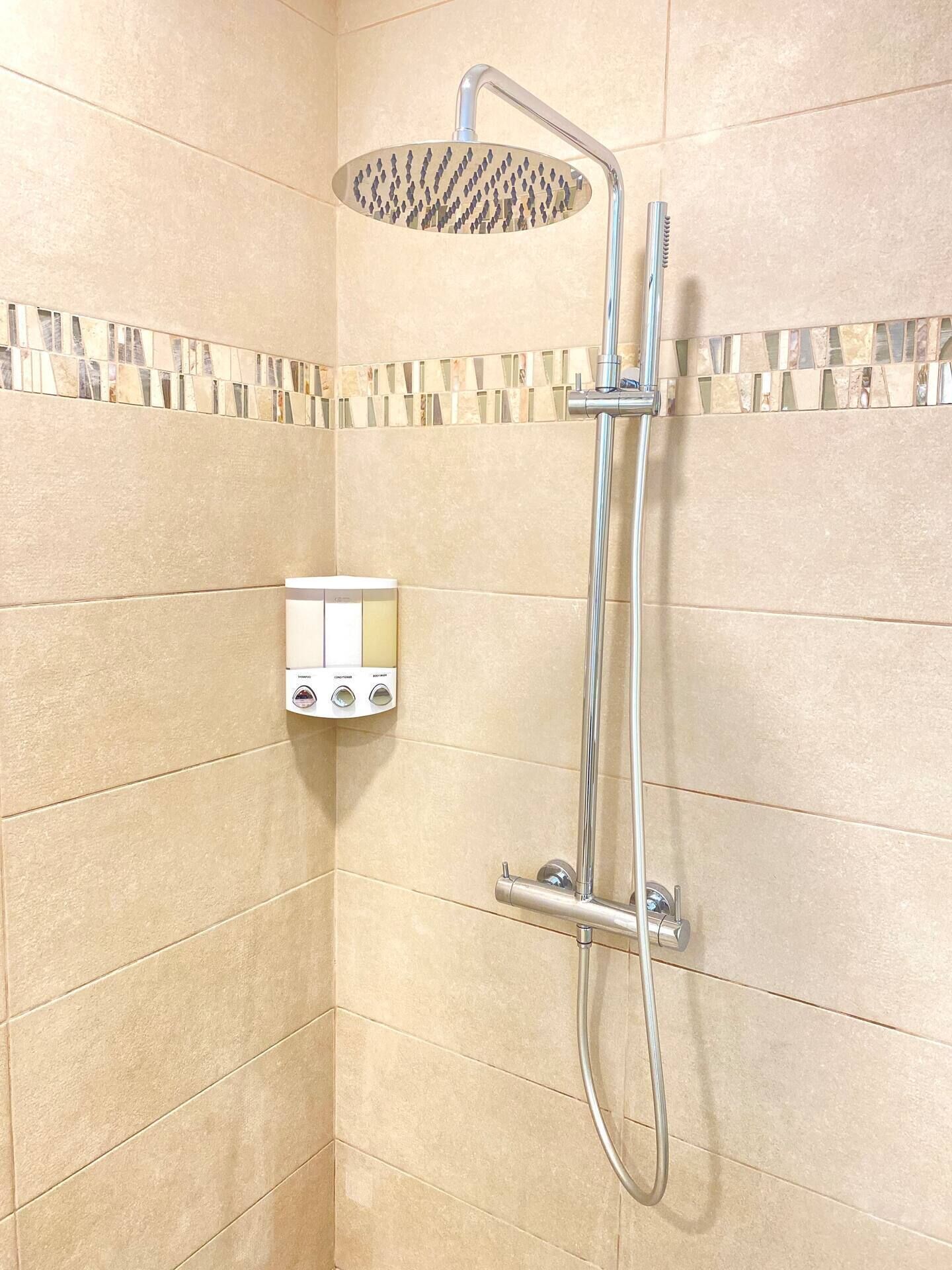 A shower with a handheld showerhead and a wall-mounted control panel.