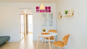 Un espace repas moderne avec une table ronde, quatre chaises en osier et un meuble vitré placé au-dessus.