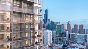A modern high-rise building with multiple balconies, large windows, and a city skyline in the background. - Level Chicago Fulton Market (Chicago)