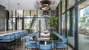 Une salle de conférence moderne, dotée d’une longue table, de chaises bleues et d’un luminaire au plafond au design original.