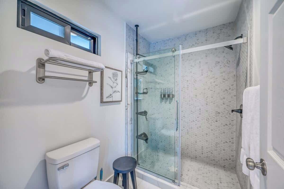 Un bagno moderno con cabina doccia in vetro, un water e un piccolo sgabello.