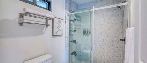 Un bagno moderno con cabina doccia in vetro, un water e un piccolo sgabello.