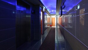 A modern hallway with a blue-lit ceiling, a red carpet, and a glass wall on one side.