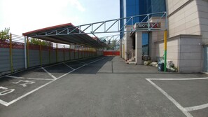 A parking area with marked spaces, a covered walkway, and a building with a 'Motel' sign. - LOL Motel (Daegu)