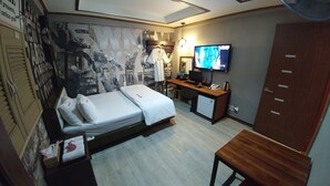A hotel room with a bed, a desk, a television, and a wardrobe.