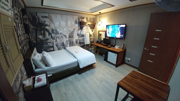 A hotel room with a bed, a desk, a television, and a wardrobe.