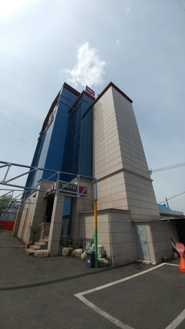A hotel with a modern design, featuring a prominent glass facade and a traditional brick section. - LOL Motel (Daegu)