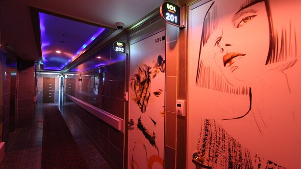 A hotel corridor with doors labeled 201 and 202, a security camera, and a wall with a large, abstract mural.