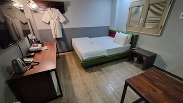 A hotel room with a bed, a desk, a chair, a TV, and a wardrobe.