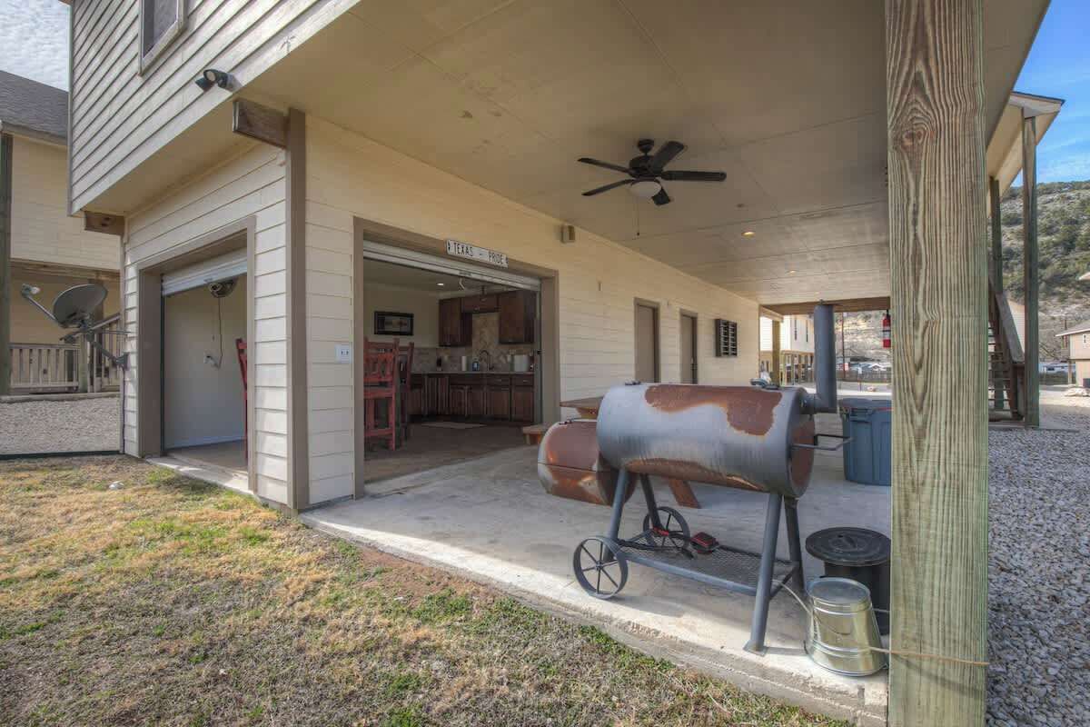 A covered patio with a barbecue grill, a ceiling fan, and a sign indicating a Texas-themed restaurant.