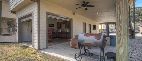 A covered patio with a barbecue grill, a ceiling fan, and a sign indicating a Texas-themed restaurant.