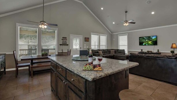 A spacious kitchen with a large island, dark wood cabinets, and a dining area with a table and chairs. - Let's Go Tubing! Awesome House-next to River! (New Braunfels)
