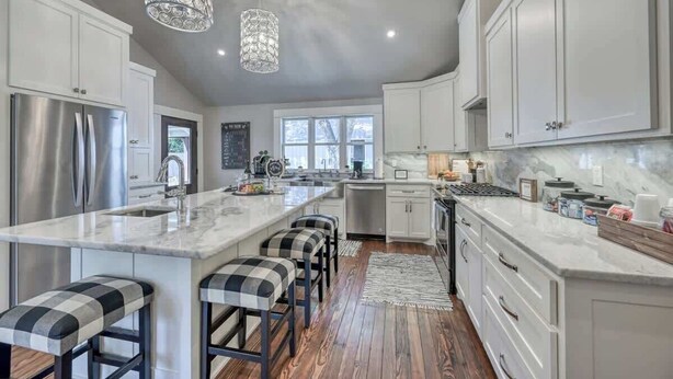 A modern kitchen with a large island, stainless steel appliances, and bar stools.